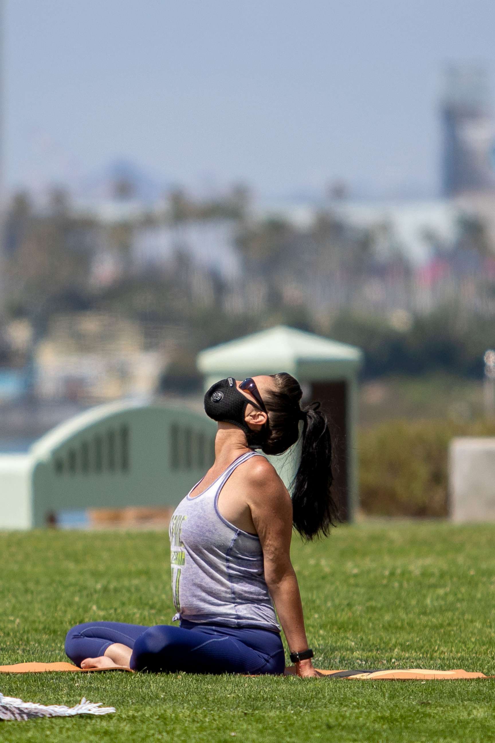 PHOTO: A woman wearing a facemask practices yoga at Bluff park in Long Beach, Calif., July 14, 2020.