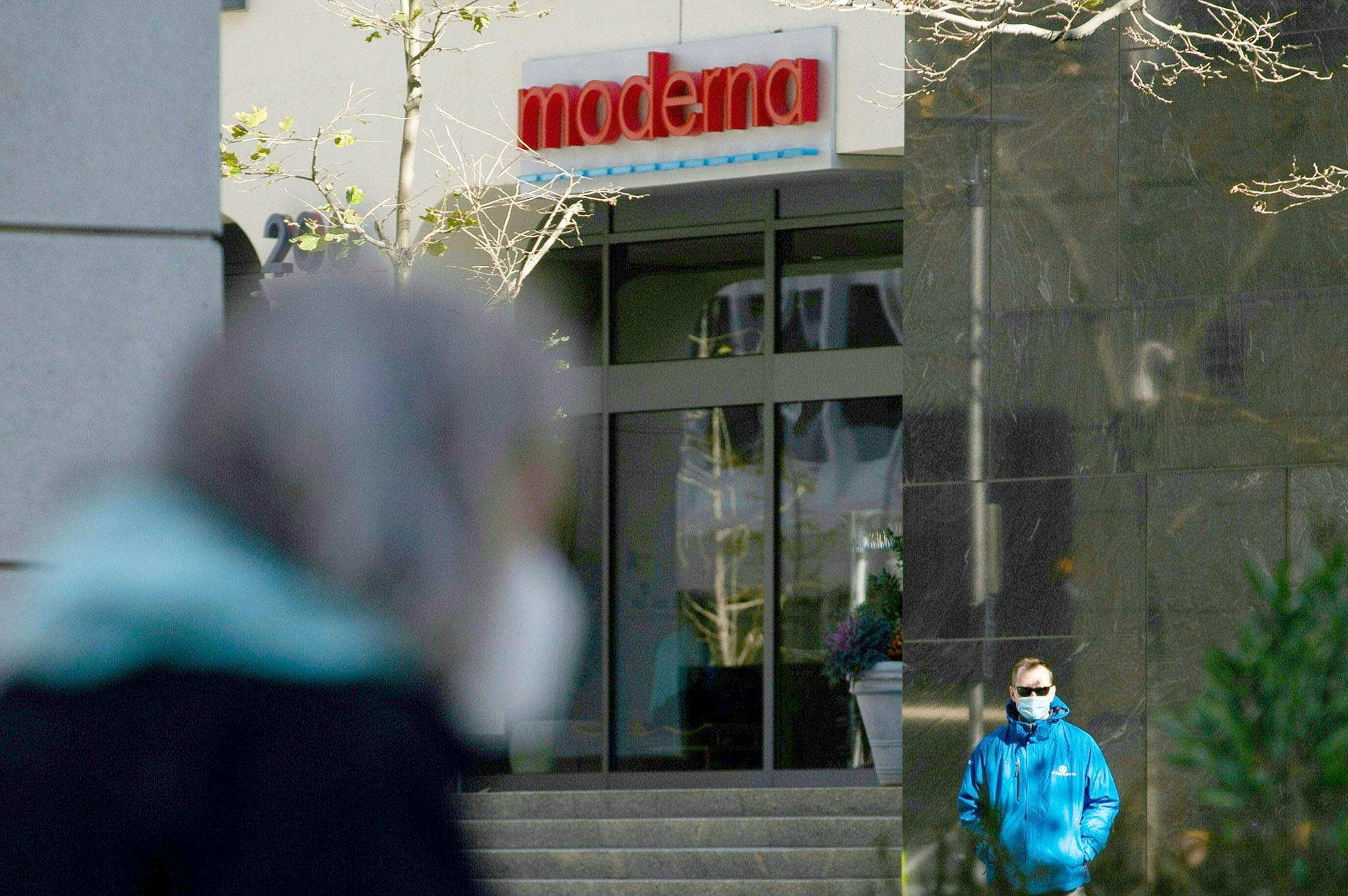 PHOTO: Pedestrians wearing face masks walk past the headquarters of biotechnology company Moderna in Cambridge, Mass., Nov. 16, 2020.