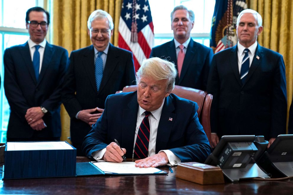 PHOTO: President Donald Trump signs the coronavirus stimulus relief package in the Oval Office at the White House, March 27, 2020.