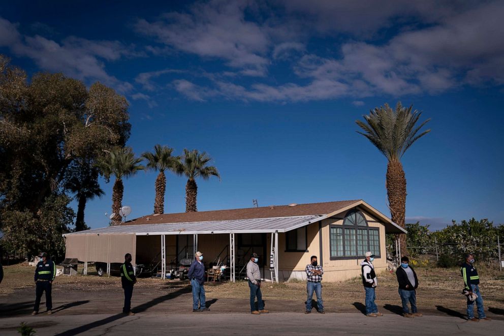 PHOTO: Farm workers wait in line to receive the Pfizer-BioNTech COVID-19 vaccine at Tudor Ranch in Mecca, Calif., Jan. 21, 2021.