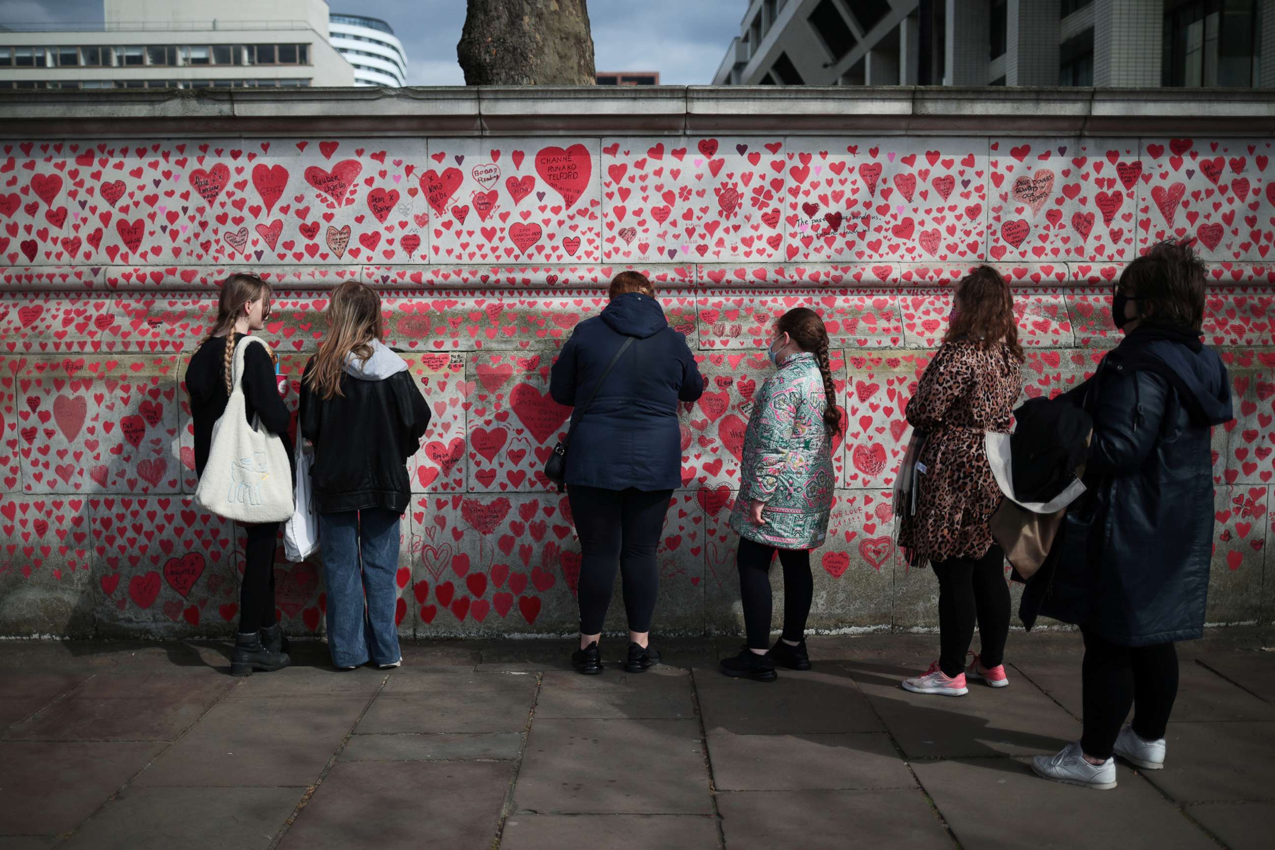 PHOTO: People stand by the National Covid Memorial wall beside St Thomas' hospital set as a memorial to all those who have died so far in the U.K. from the coronavirus disease, in London, April 8, 2021.