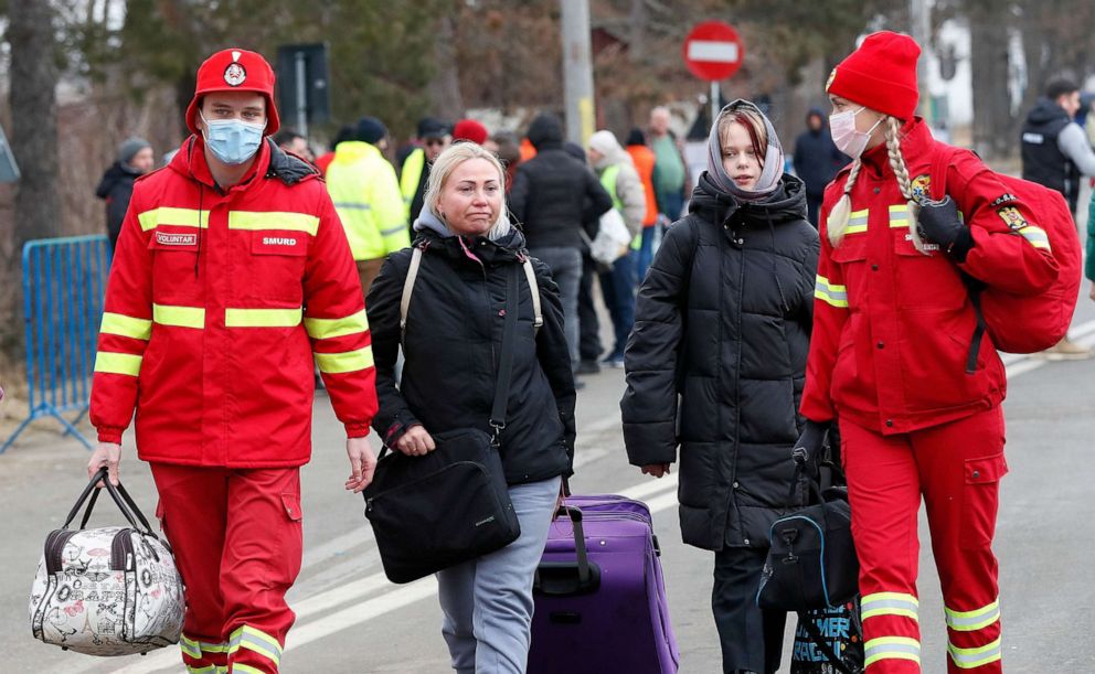 PHOTO: Ukrainian refugees, helped by Romanian paramedics, pass the Romanian-Ukrainian border crossing point in Siret, northern Romania, on Feb. 26, 2022.