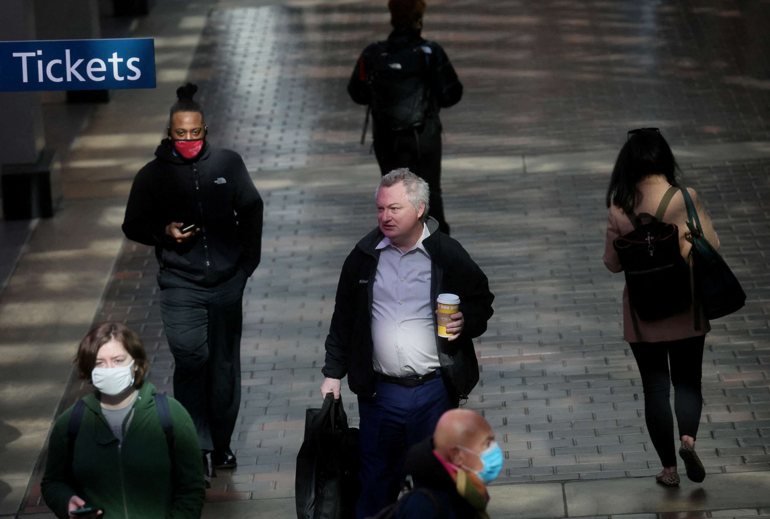 PHOTO: People walk with and without masks following a federal judge's ruling that the 14-month-old mask mandate was unlawful, at Union Station, in Washington, D.C., April 19, 2022. 