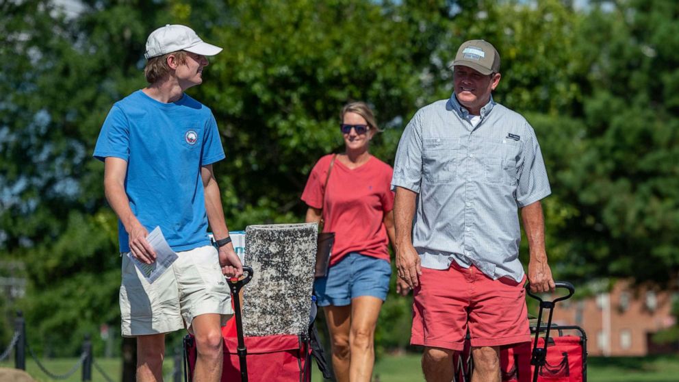 PHOTO: Baylor Garland, left, arrives to move in for his freshman year, assisted by his father Alan, right and mother, Teena, after they traveled from Eaton, Ga., at the University of Alabama campus on Aug. 15, 2020, in Tuscaloosa, Ala.