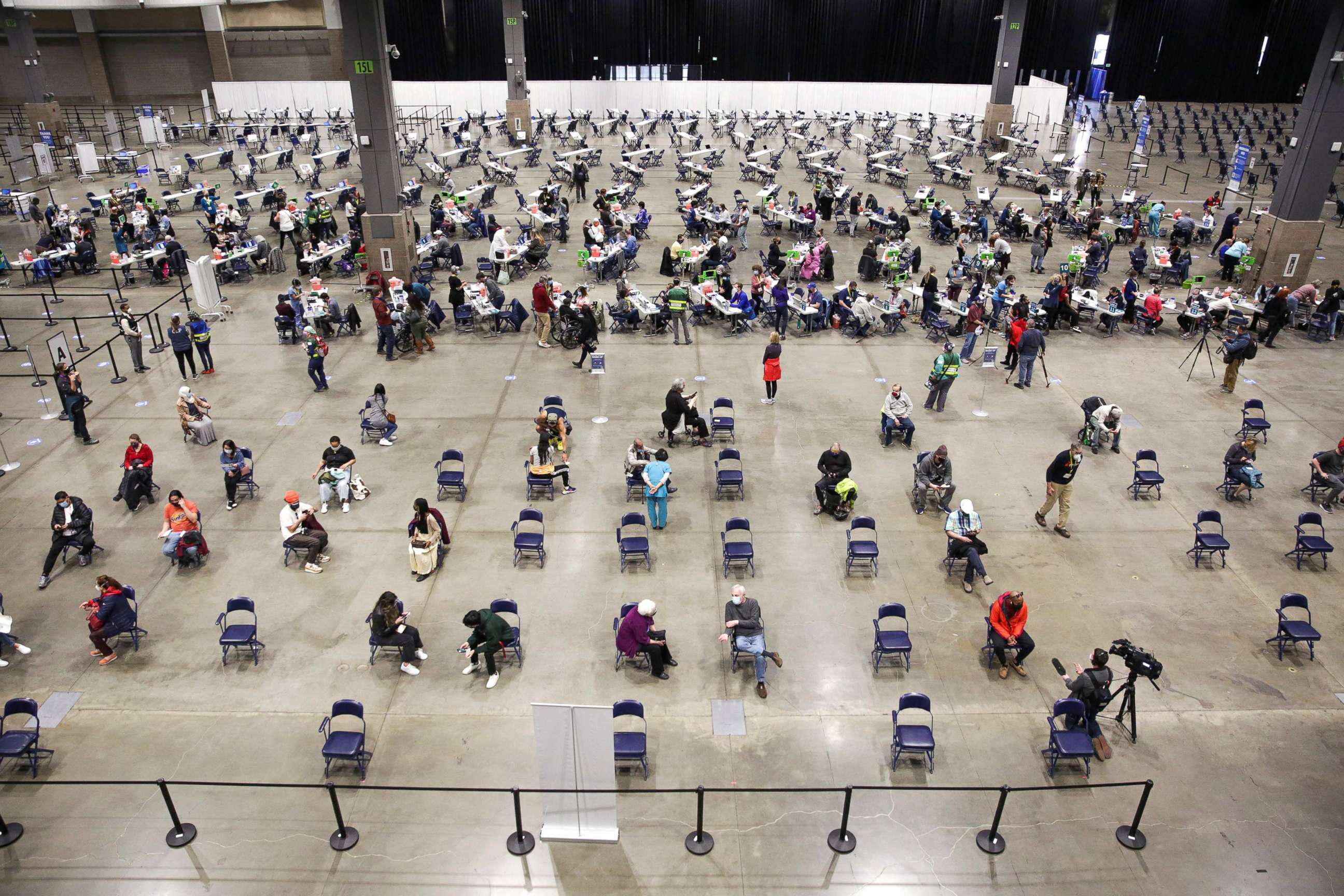 PHOTO: Patients sit in an observation area after receiving the Pfizer Covid-19 vaccine, bottom, at a mass vaccination site at the Lumen Field Event Center in Seattle, March 13, 2021.