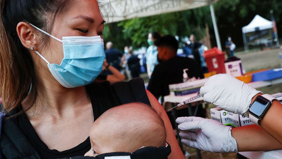 PHOTO: A person receives a COVID-19 vaccination dose, while carrying a baby in tow, on Aug. 3, 2021, in Los Angeles.