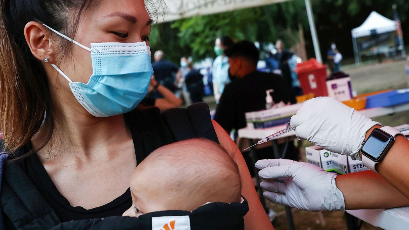 PHOTO: A person receives a COVID-19 vaccination dose, while carrying a baby in tow, on Aug. 3, 2021, in Los Angeles.