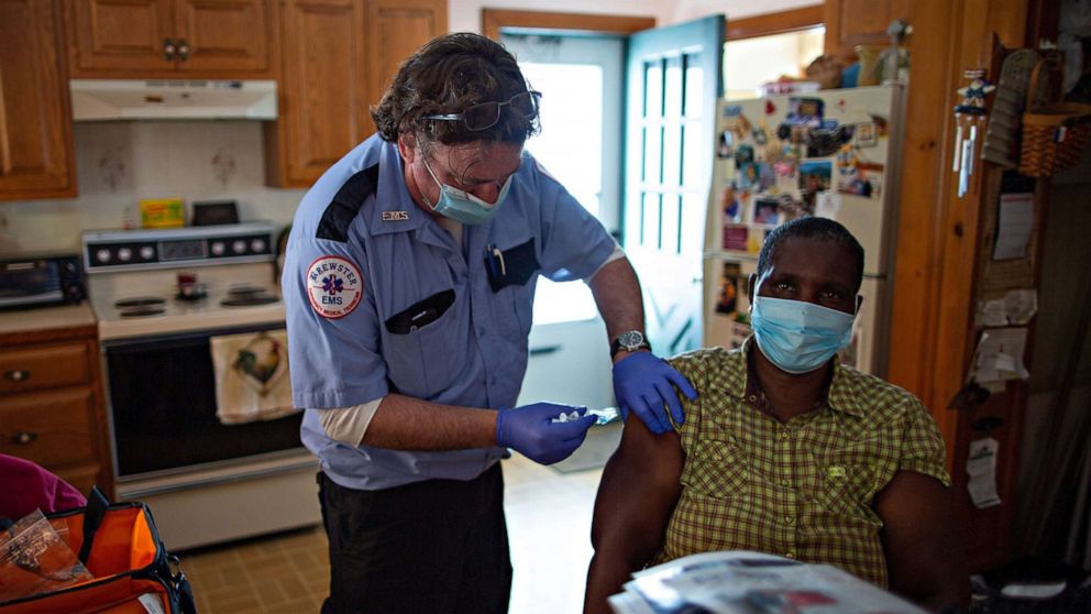 Paramedic Rob Barss administers the J & J COVID-19 vaccine to Mary Wanjiku,a health care aid to a Leominster home-bound resident, as part of the pilot mobile vaccine distribution program called, Last Mile Vaccine Delivery,in Leominster, Mass.