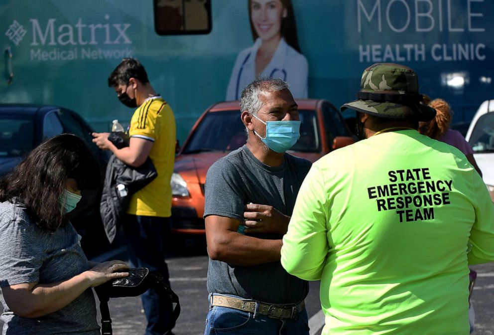 PHOTO: People register at a pop-up COVID-19 vaccination site in the parking lot of Bravo Supermarket in a predominantly Black and Hispanic neighborhood of Orlando, Fla., April 9, 2021. 