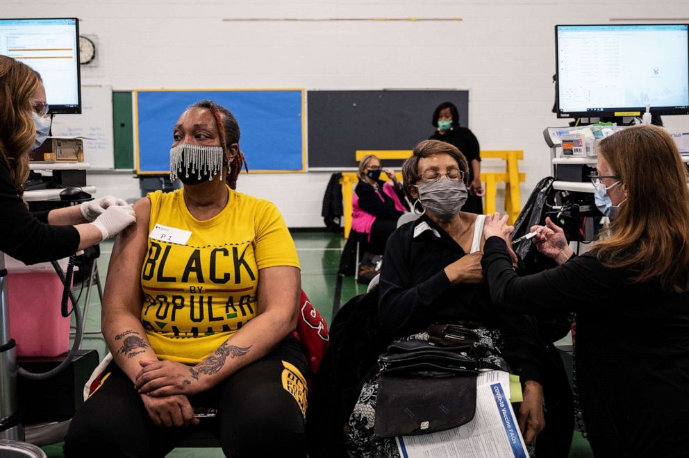 PHOTO: Andrea Moore, left sits as her mother, Alma Penn as she receives her COVID-19 vaccine in the gymnasium at Whitney M. Young Elementary School on April 2, 2021 in Louisville, Ky.