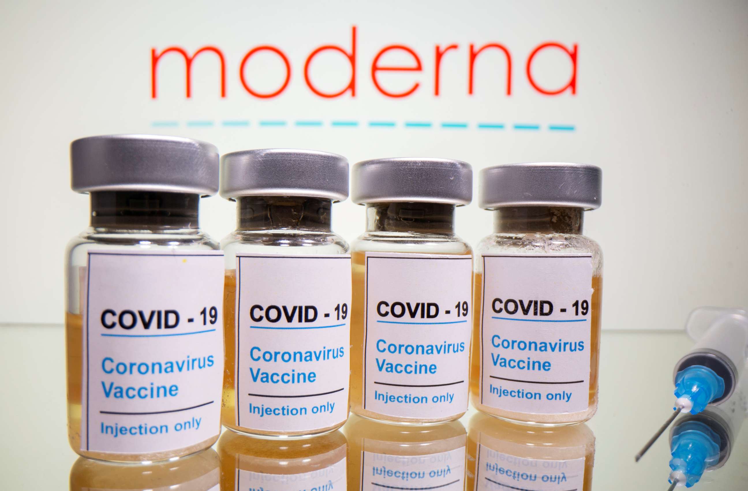 PHOTO: Vials with a sticker reading "COVID-19/Coronavirus vaccine/Injection only" and a syringe are seen in front of a displayed Moderna logo in this illustration taken October 31, 2020. 