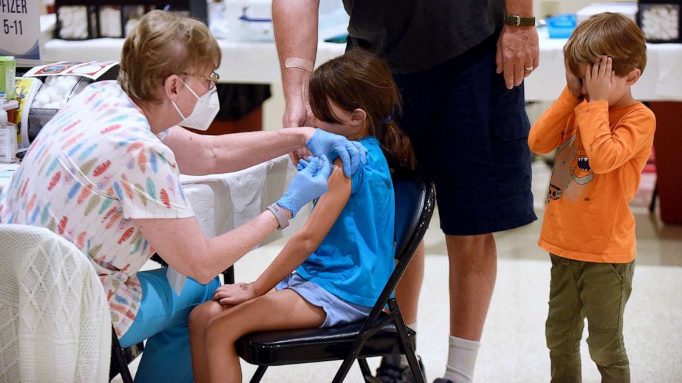 PHOTO: A nurse gives a little girl a shot of the Pfizer COVID-19 vaccine while her brother covers his eyes at a vaccination site for 5-11 year-olds in Altamonte Springs, Fla., Nov. 9, 2021.