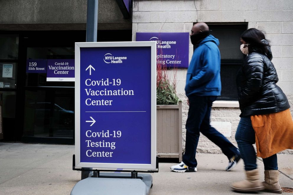 PHOTO: People walk by a sign for both a COVID-19 testing clinic and a vaccination location outside of a Brooklyn hospital on Jan. 27, 2021, in New York.