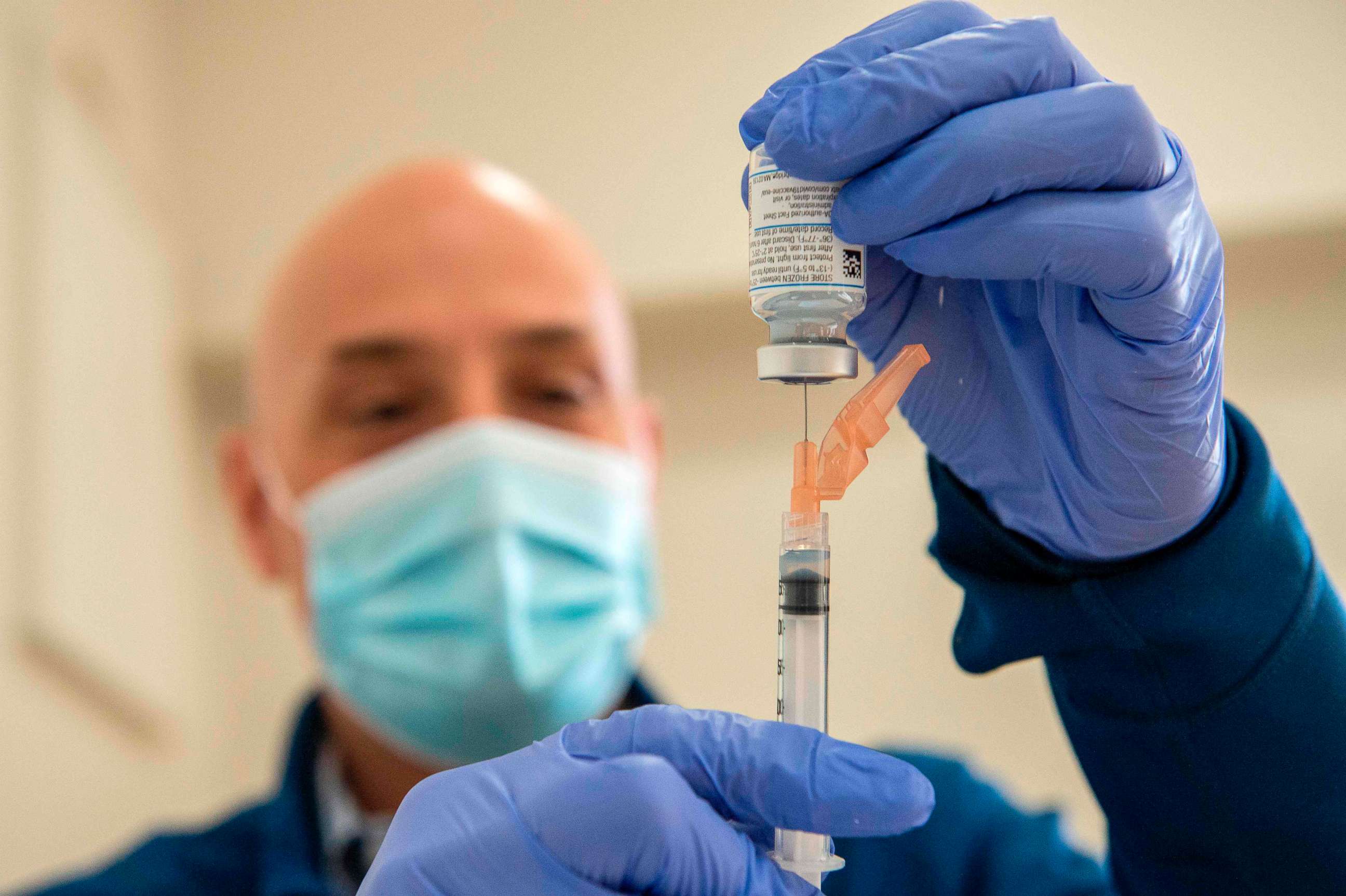 PHOTO: Pharmacist Jason Hyde fills syringes with the Moderna Covid-19 vaccine as first responders wait to receive it at UMass Memorial Hospital in Marlborough, Massachusetts on January 12, 2021. 