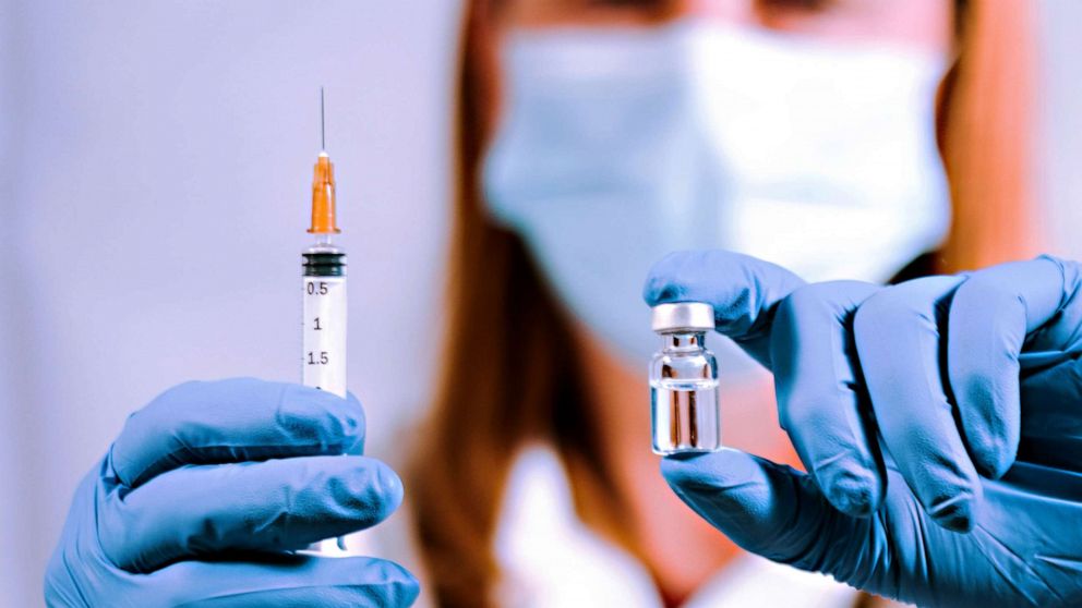 PHOTO: A woman in medical garb holds a syringe and vial.