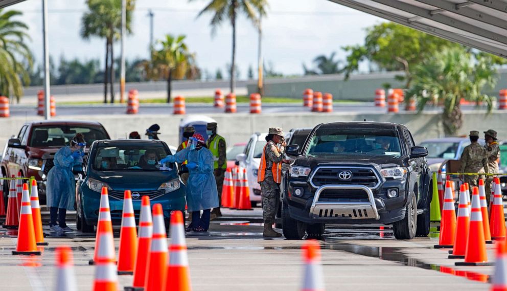 PHOTO: A National Guard troop directs cars as a citizens is being tested by a healthcare workers at the COVID-19 drive-thru testing center at Hard Rock Stadium in Miami Gardens as the coronavirus pandemic continues on Sunday, July 19, 2020. 