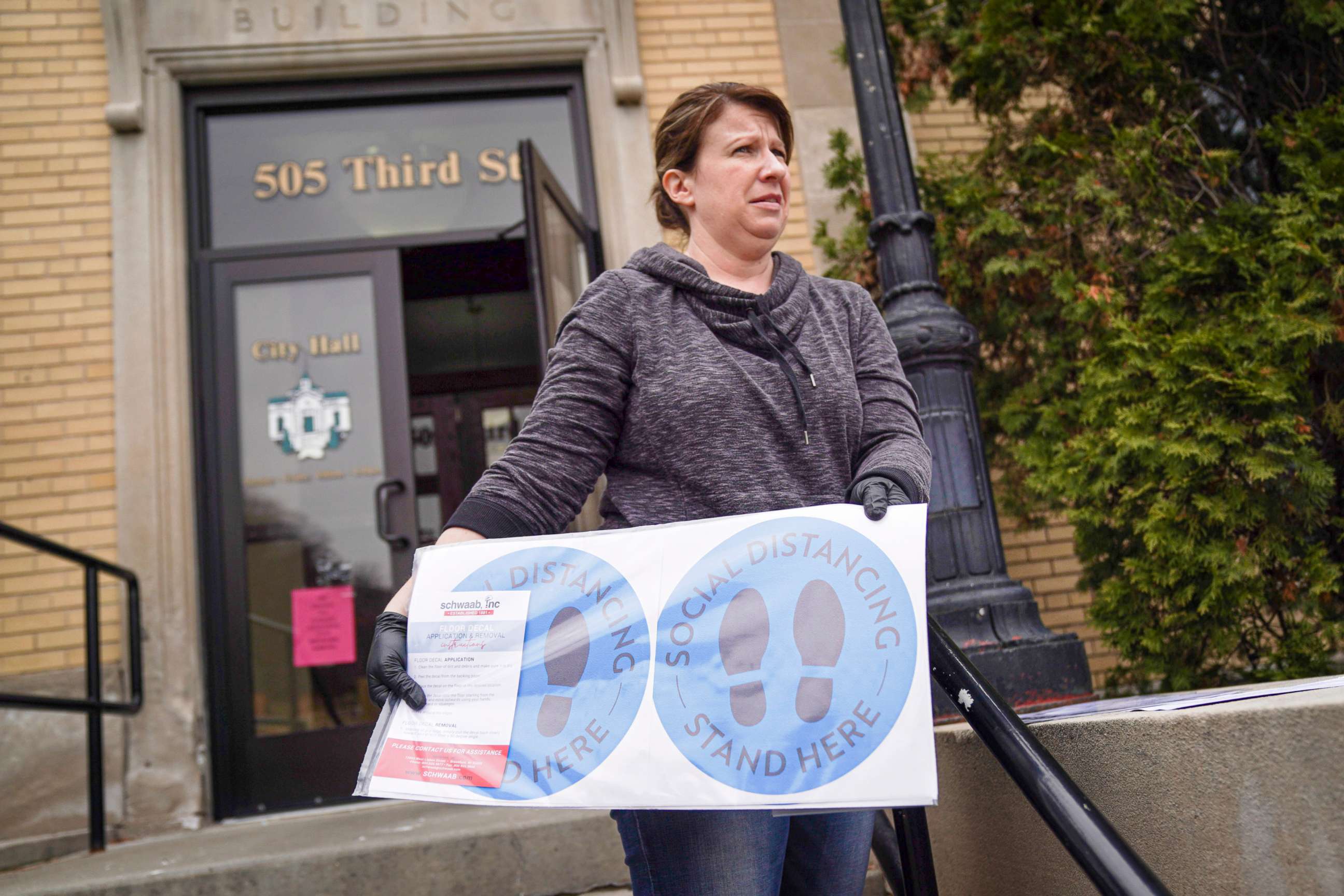 Hudson, Wis., city clerk Becky Eggen displays some of the health alert and social distancing signs Monday, April 6, 2020, that were to be used in Tuesday's election, postponed by the governor Monday afternoon. 