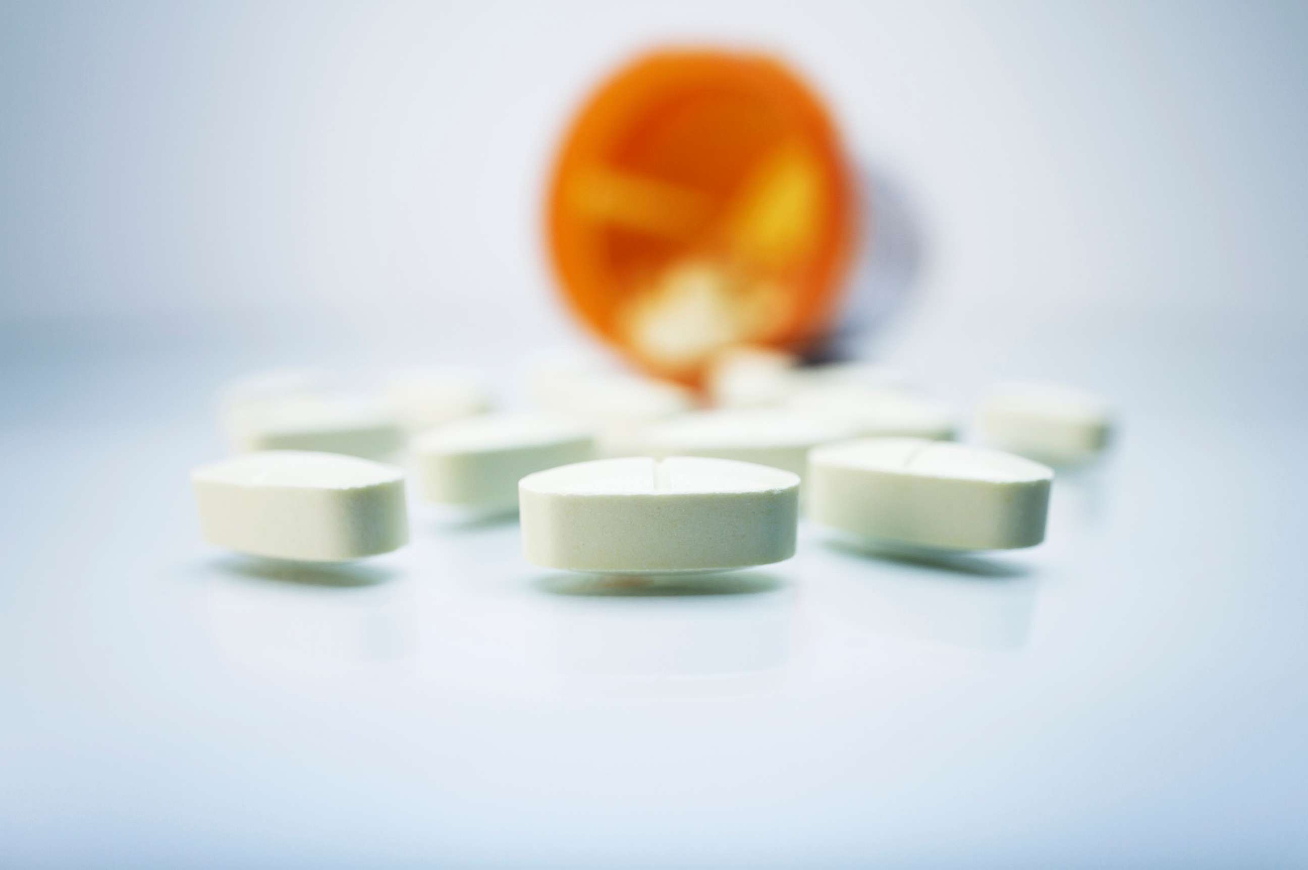 PHOTO: White pills and a plastic prescription pill container. 