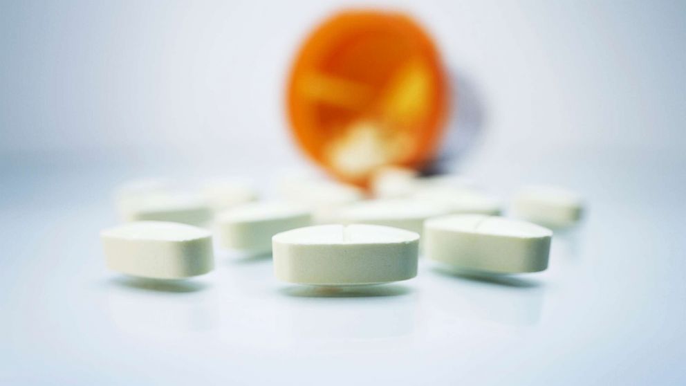 PHOTO: White pills and a plastic prescription pill container. 