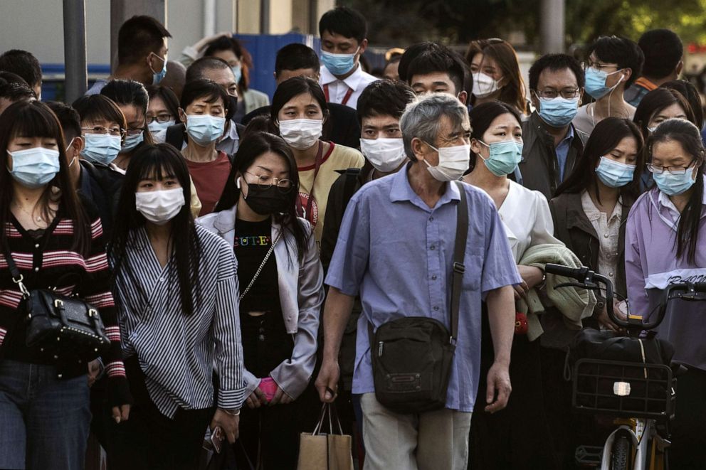 PHOTO: Chinese commuters wear protective masks as they wait to cross an intersection at the end of the workday during rush hour, May 18, 2020, in Beijing, China.