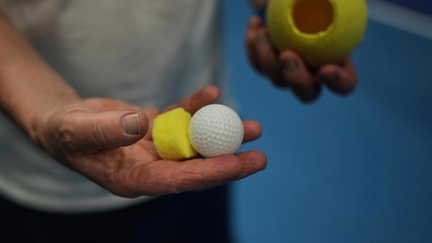 Tennis coach, Lee Neale, shows a ball used for visually impaired tennis during a training session in London, Wednesday, May 14, 2025. (AP Photo/Kin Cheung)
