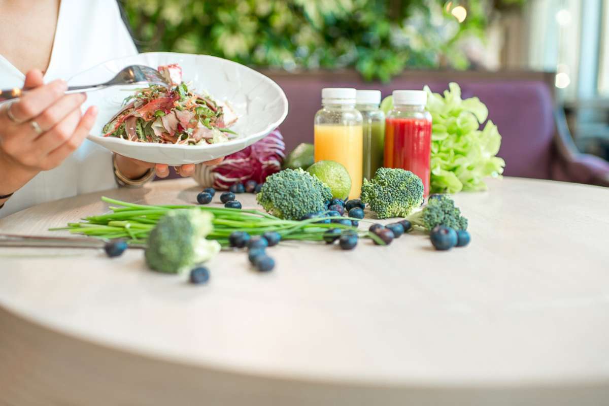 PHOTO: A woman eats a salad at the table full of healthy food ingredients and smoothies in this undated stock photo.