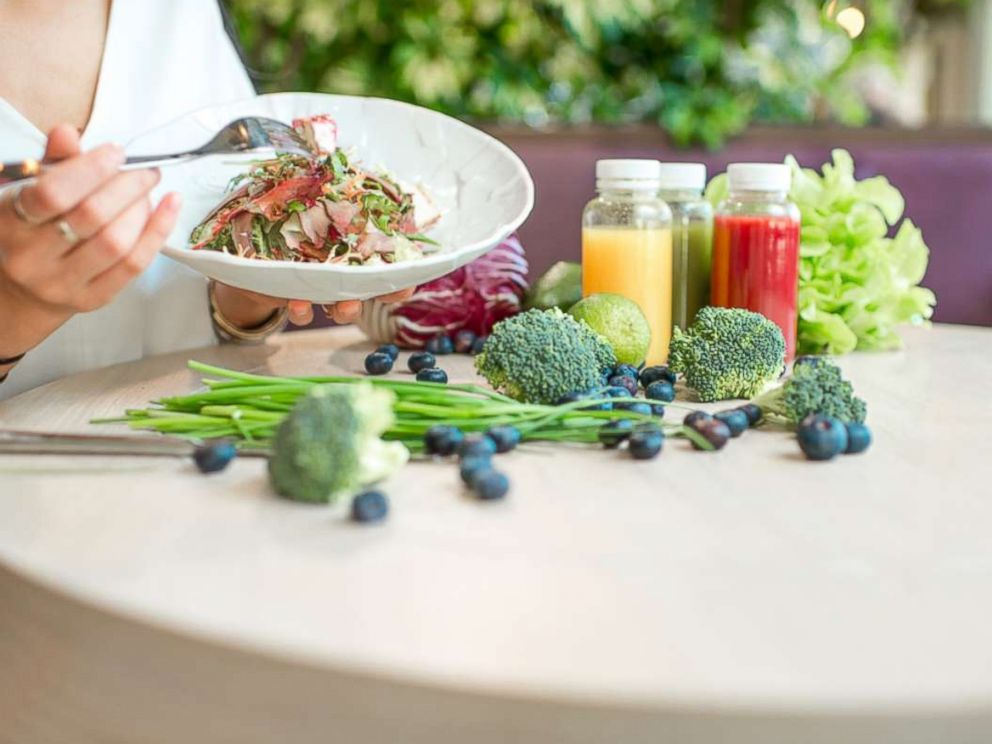 PHOTO: A woman eats a salad at the table full of healthy food ingredients and smoothies in this undated stock photo.