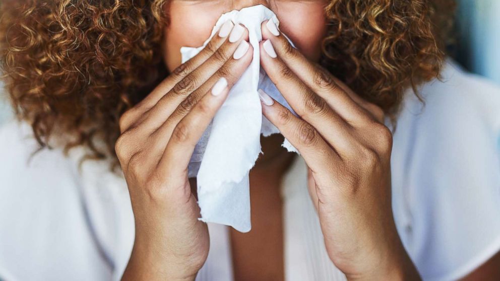 A woman uses a tissue to sneeze in this undated stock photo.