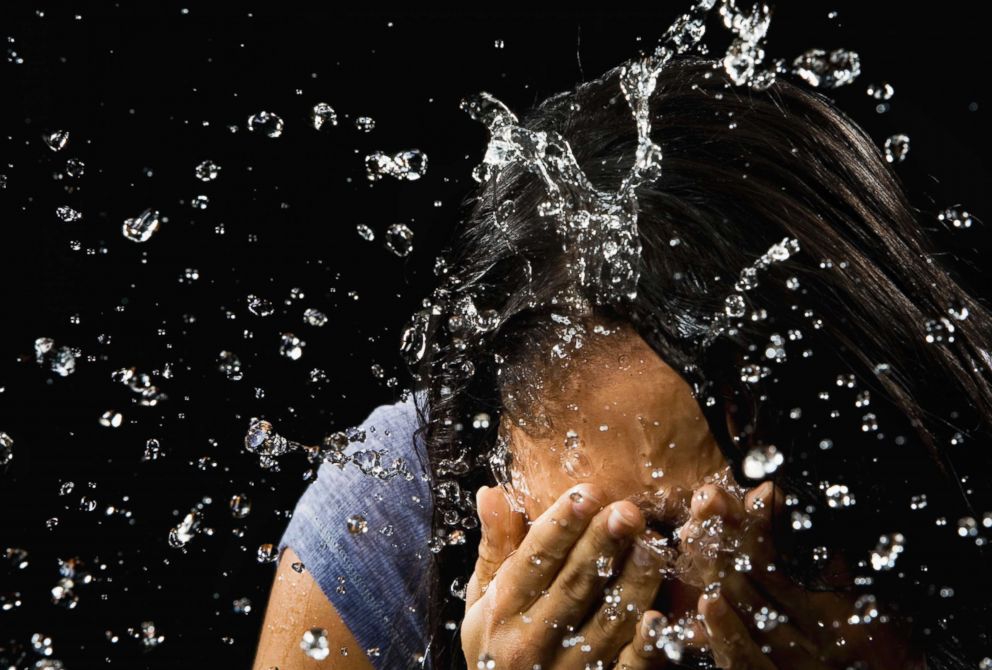 PHOTO: Stock photo of a woman splashing her face with water.