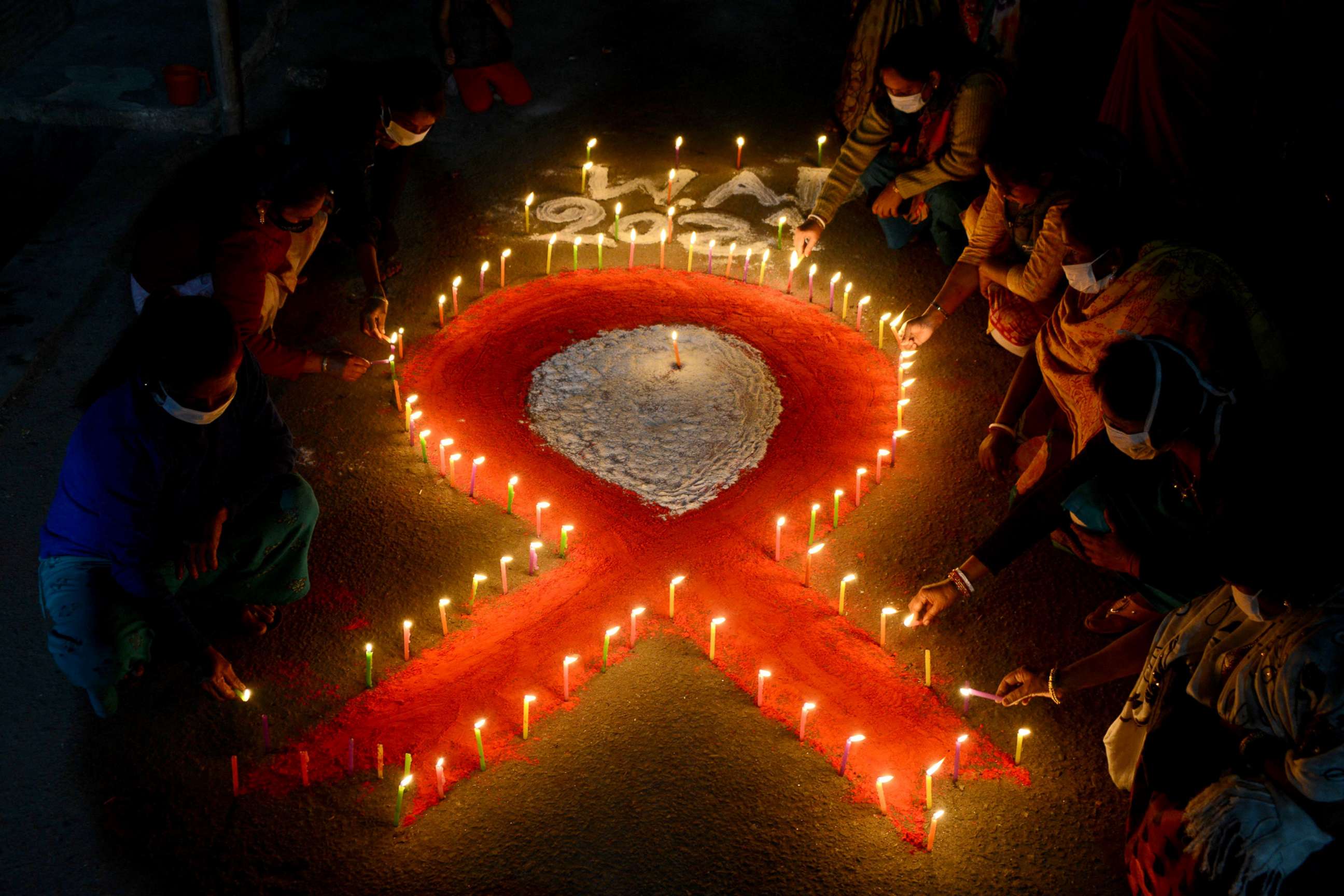 PHOTO: Volunteers and sex workers light candles forming the shape of a red ribbon during an awareness event on the eve of the 'World AIDS Day' in Siliguri, India,  Nov. 30, 2021. 