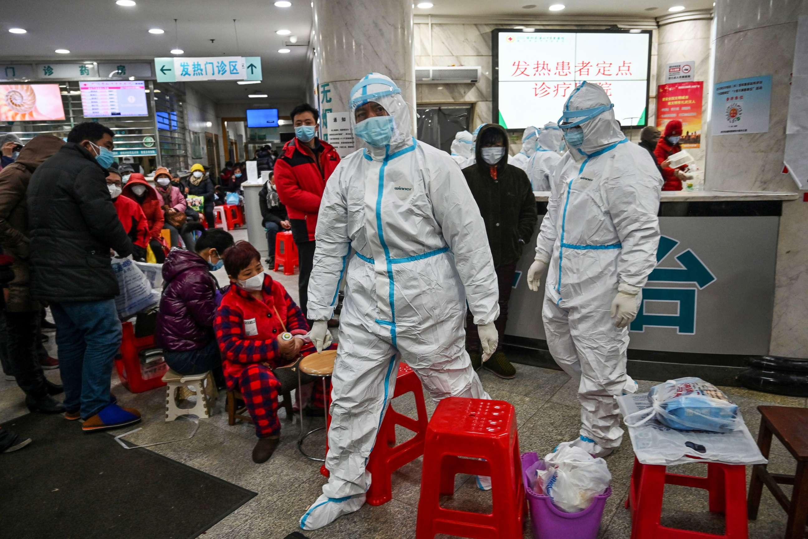 PHOTO: Medical staff members wearing protective clothing walk next to patients waiting for medical attention at the Wuhan Red Cross Hospital in Wuhan, China, Jan. 25, 2020.