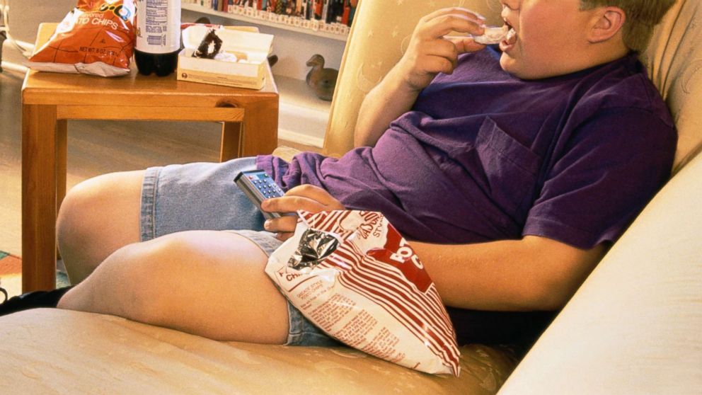 In this undated stock photo, a boy eats junk food while watching tv.