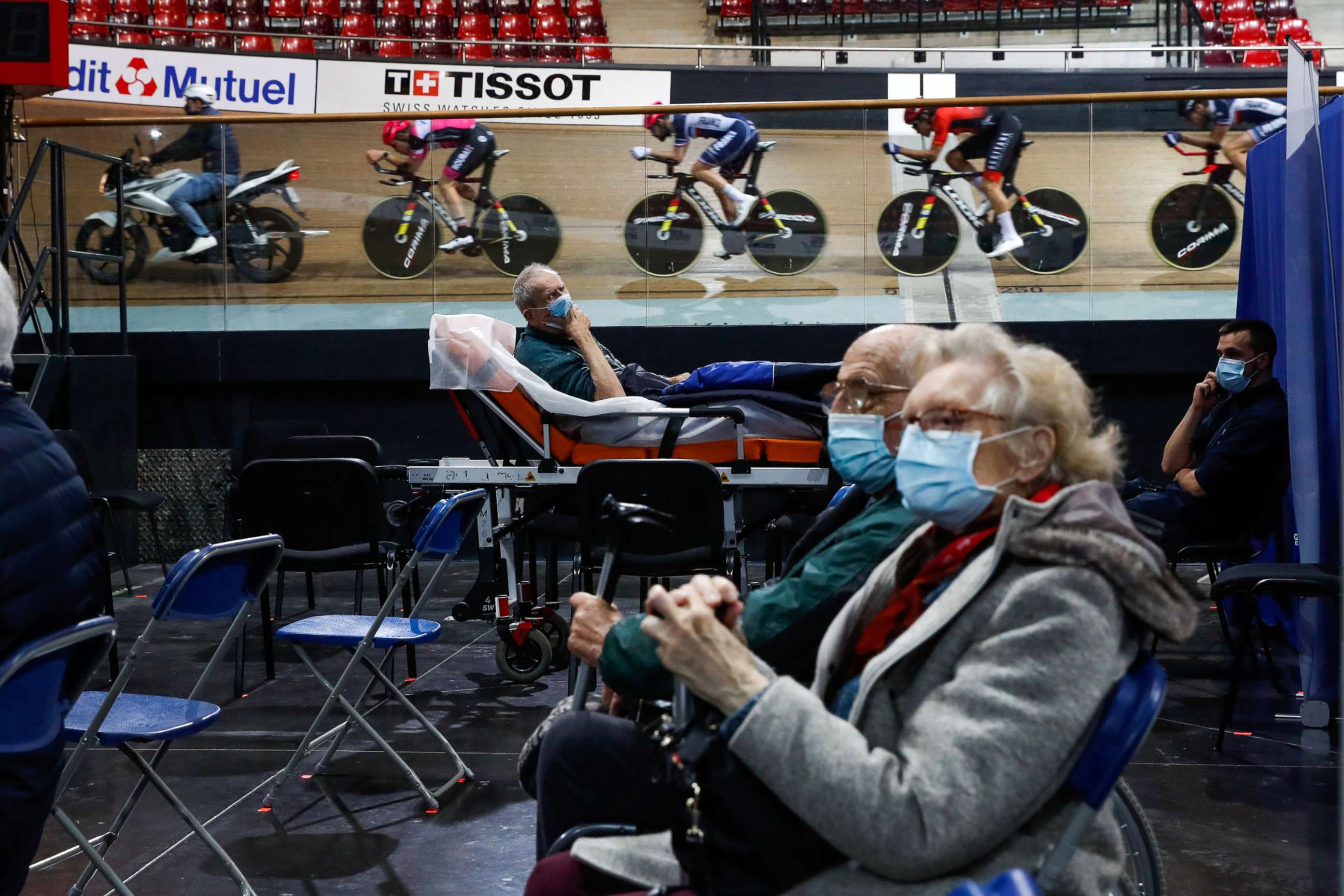 PHOTO: France's national cycling team trains as people wait to get a dose of the Pfizer-BioNTech COVID-19 vaccine at the indoor Velodrome National of Saint-Quentin-en-Yvelines in Montigny-le-Bretonneux, France, March 26, 2021.