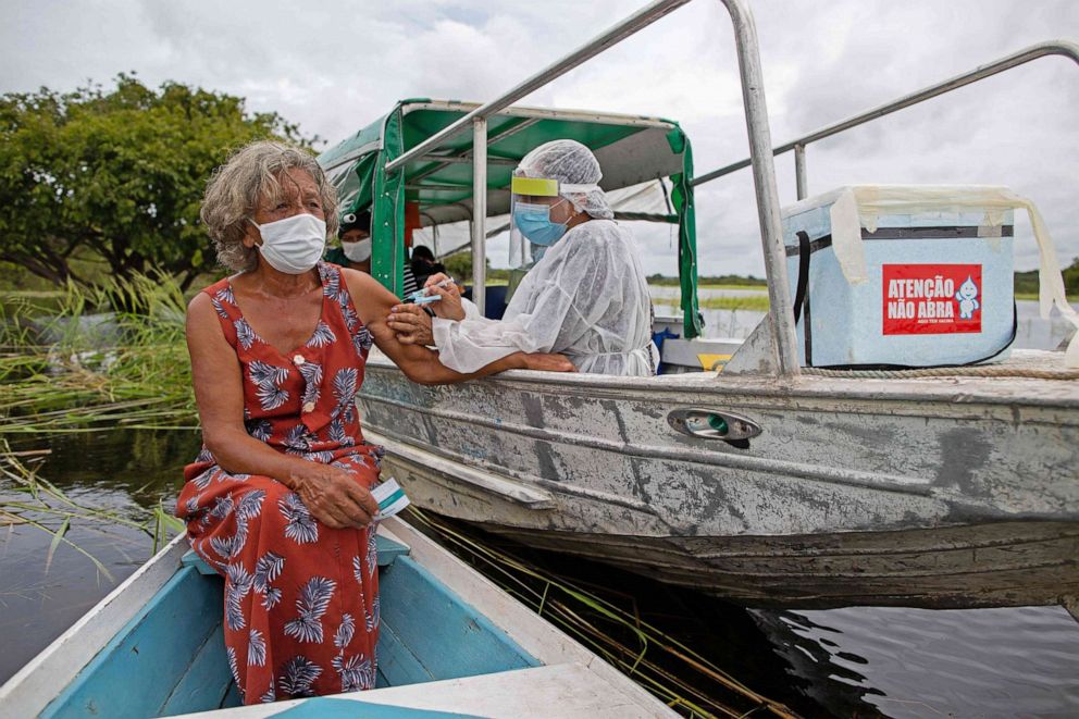 PHOTO: Olga D'arc Pimentel, 72, is vaccinated by a health worker with a dose of the Oxford-AstraZeneca COVID-19 vaccine in the Nossa Senhora Livramento community on the banks of the Rio Negro near Manaus, Brazil on Feb. 9, 2021.