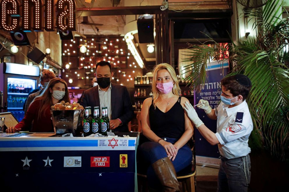 PHOTO: A woman receives a COVID-19 vaccine dose as part of a Tel Aviv municipality initiative offering a free non-alcoholic drink at a bar to residents getting the shot, in Tel Aviv, Israel on Feb. 18, 2021.