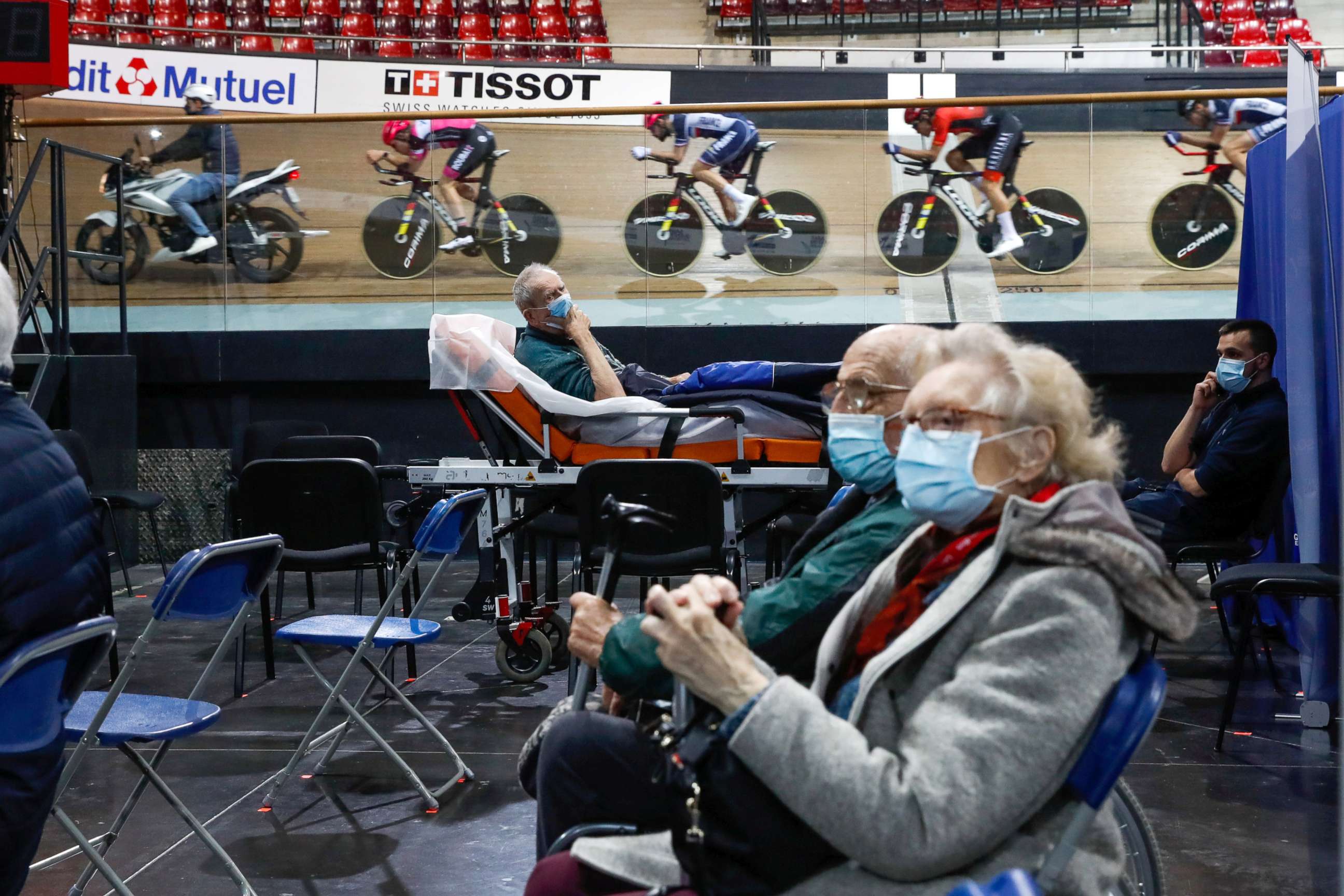 PHOTO: France's national cycling team trains as people wait to get a dose of the "Comirnaty" Pfizer-BioNTech COVID-19 vaccine at the indoor Velodrome National of Saint-Quentin-en-Yvelines in Montigny-le-Bretonneux, southwest of Paris, March 26, 2021.