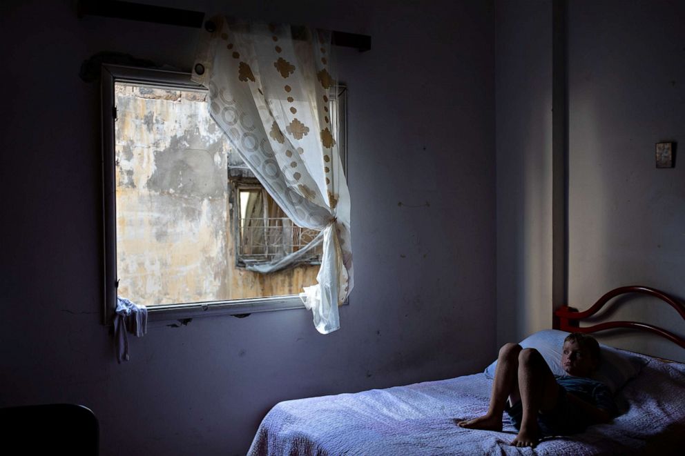 PHOTO: Elie Batrouni, 9, lies on a bed next to a damaged window at his home in Karantina, Beirut, Aug. 13, 2020.