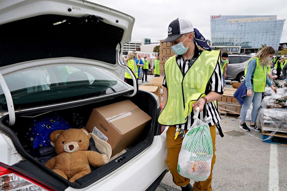 PHOTO: Volunteer Henry Fillmore of Arlington, Texas, places a frozen turkey in to the trunk of a vehicle during a Tarrant Area Food Bank mobile pantry distribution event in Arlington, Texas, Nov. 20, 2020.