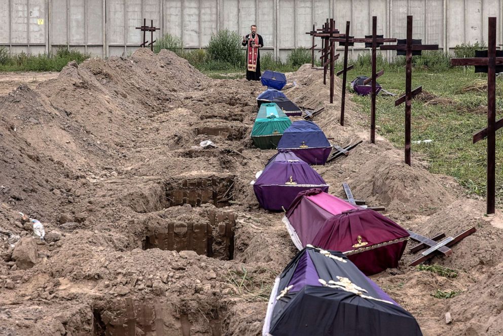 PHOTO: Orthodox priest Andrii Halavin blesses the remains of unidentified people who were killed in the Bucha district at the time of the Russian occupation, during the mass burial at a cemetery in Bucha, northwest of Kyiv, Ukraine, Aug. 11, 2022.