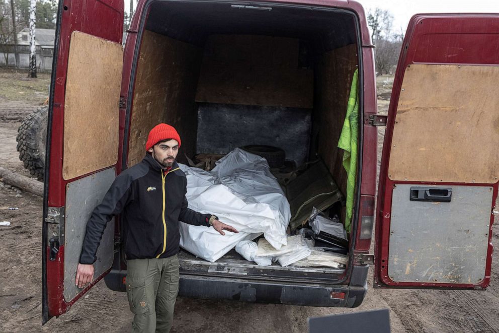 PHOTO: Vitalii Udod, a volunteer from Kyiv, stands next to a van loaded with two dead bodies in Yahidne.