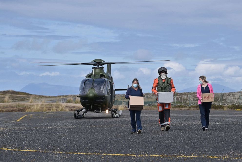 PHOTO: Ireland: Nurses Margaret Lavelle, left, and Louise Fleming, right, take delivery of COVID-19 vaccines from an Irish Air Corps crew member on May 18, 2021, in Inishbofin, Ireland.