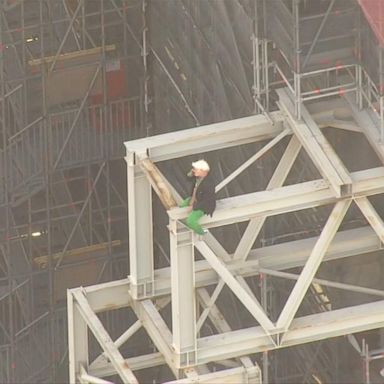 The person can be seen sitting high above the street on the construction site. 