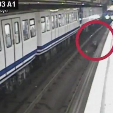 The video cuts away just as onlookers jump onto the tracks to help the woman.