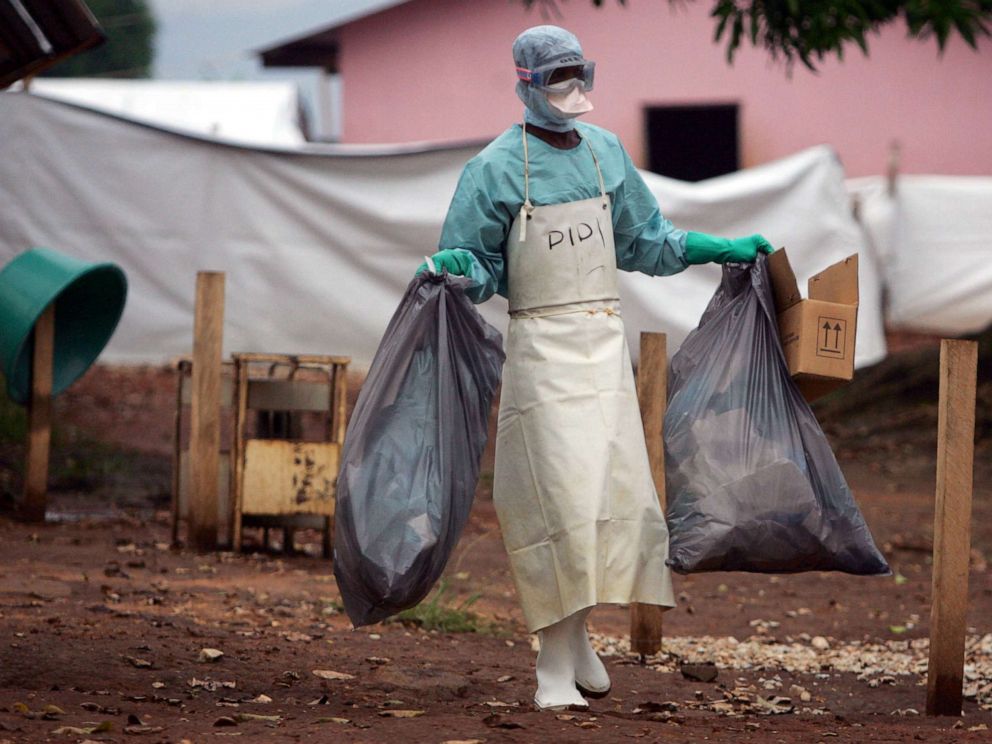 PHOTO: In this April 20, 2005 file photo a health worker in protective clothing carries waste for disposal outside the isolation ward where victims of the deadly Marburg virus are treated in the northern Angolan town of Uige.