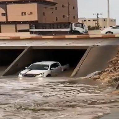 Vehicles carefully push through a flooded tunnel