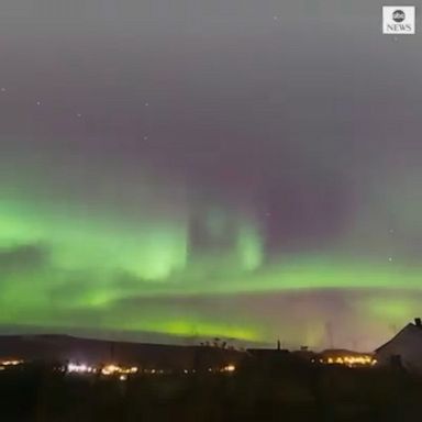 A photographer captured time-lapse footage of the colorful northern lights over houses and mountains in Norway.