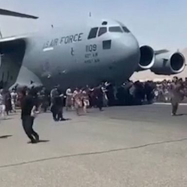 Video shows hundreds of people running alongside a U.S. Air Force C-17 transport plane as it moves down a runway of the Kabul airport.