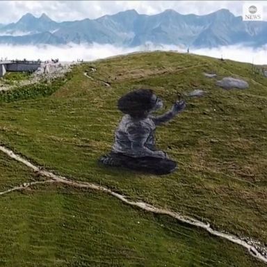 Flight of fancy: A graffiti artist used the side of a Swiss mountain for his latest project, a huge mural of a child looking at clouds.