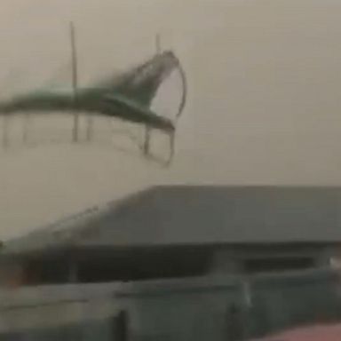 Damaging winds launch a trampoline into the air and catapult it down a street.