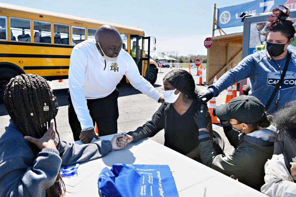 Senior Sudeen Pryce receives support from classmate Alexia Phipps, East Hartford High School Intervention Coordinator Mark Brown and EMT Katrinna Greene as RN Kaylee Cruz administers the Pfizer vaccine at Pratt & Whitney Runway in East Hartford, Conn.